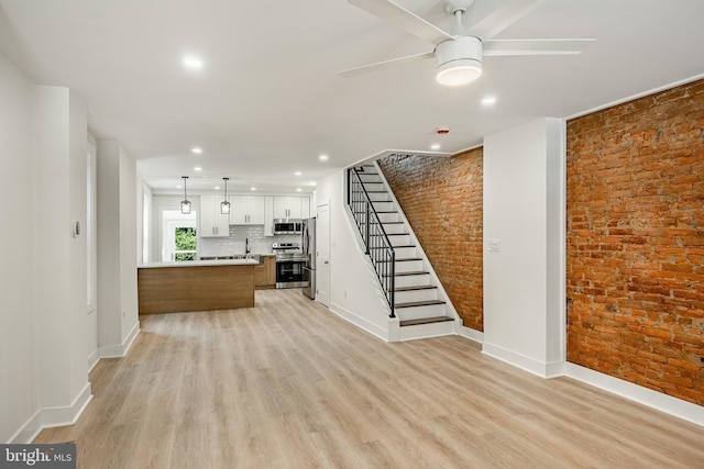 221 Ford St, Conshohocken, PA 19428 - unfurnished living room with brick wall, light wood-style floors, ceiling fan, recessed lighting, and stairs