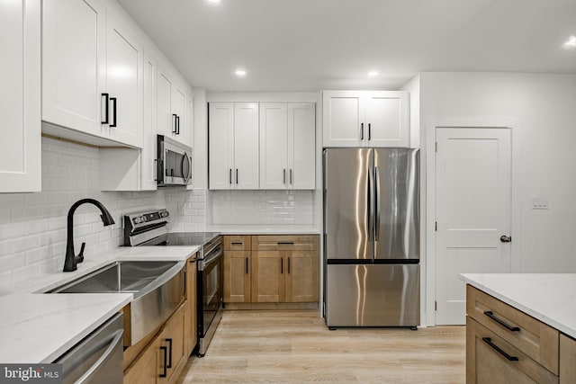 221 Ford St, Conshohocken, PA 19428 - kitchen featuring appliances with stainless steel finishes, light stone countertops, light wood-style flooring, backsplash, and recessed lighting