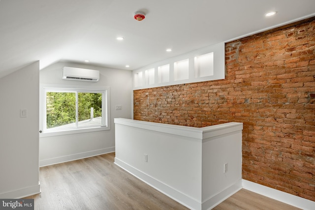 221 Ford St, Conshohocken, PA 19428 - spare room with a wall mounted air conditioner, wood finished floors, vaulted ceiling, brick wall, and recessed lighting
