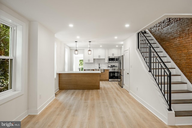 221 Ford St, Conshohocken, PA 19428 - kitchen with stainless steel appliances, a peninsula, light wood-type flooring, light countertops, and backsplash