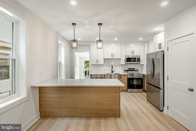 221 Ford St, Conshohocken, PA 19428 - kitchen with stainless steel appliances, a peninsula, decorative backsplash, light wood-type flooring, and white cabinetry