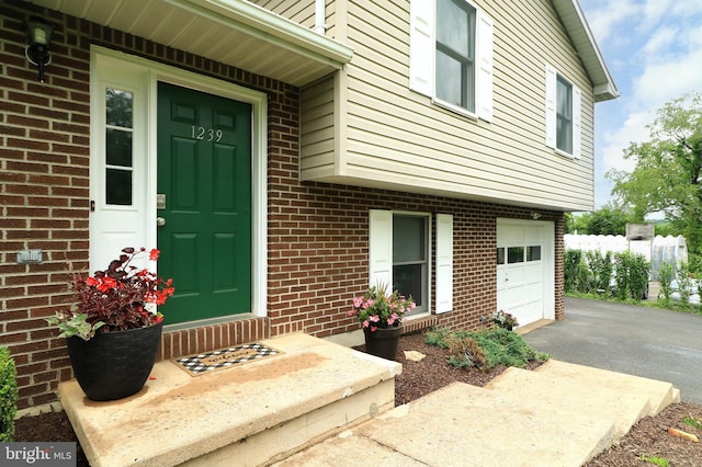 1239 Circleville Rd, State College, PA 16803 - view of exterior entry featuring a garage, brick siding, and driveway