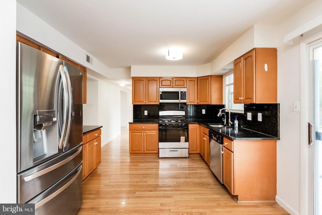 18432 Gardenia Way, Gaithersburg, MD 20879 - kitchen featuring appliances with stainless steel finishes, light wood-style flooring, decorative backsplash, brown cabinetry, and dark stone counters