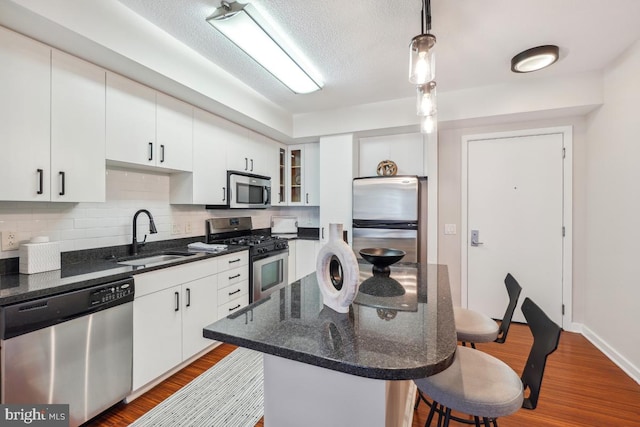 475 K St NW Unit 522, Washington, DC 20001 - kitchen featuring appliances with stainless steel finishes, a breakfast bar, tasteful backsplash, wood finished floors, and a textured ceiling
