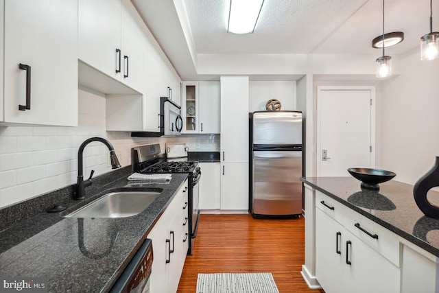 475 K St NW Unit 522, Washington, DC 20001 - kitchen featuring appliances with stainless steel finishes, tasteful backsplash, wood finished floors, white cabinetry, and decorative light fixtures
