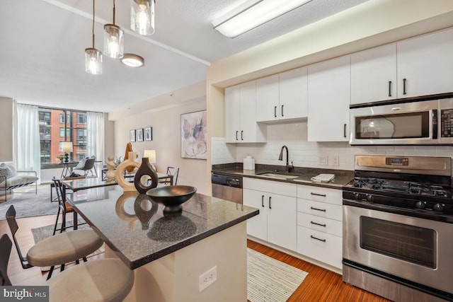 475 K St NW Unit 522, Washington, DC 20001 - kitchen featuring stainless steel appliances, a breakfast bar area, backsplash, light wood-style flooring, and white cabinets