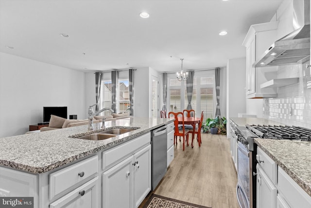 217 Hoke Farm Way, Mechanicsburg, PA 17050 - kitchen with wall chimney exhaust hood, appliances with stainless steel finishes, a chandelier, white cabinets, and light wood-type flooring
