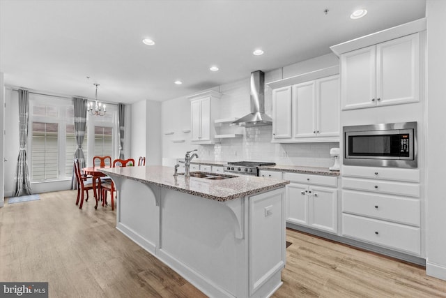 217 Hoke Farm Way, Mechanicsburg, PA 17050 - kitchen featuring wall chimney exhaust hood, stainless steel microwave, recessed lighting, light wood-type flooring, and white cabinetry