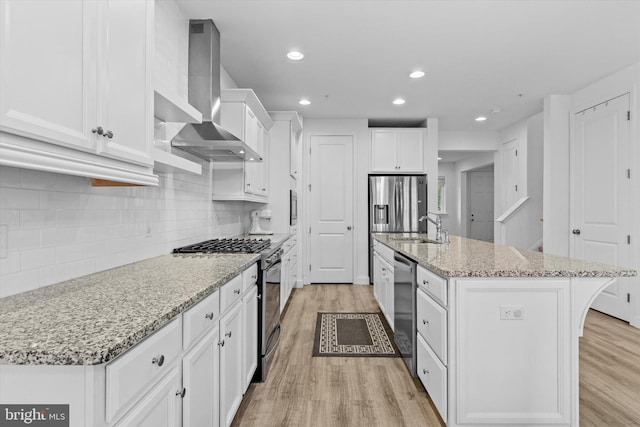 217 Hoke Farm Way, Mechanicsburg, PA 17050 - kitchen with wall chimney exhaust hood, stainless steel appliances, light wood-style floors, white cabinetry, and an island with sink