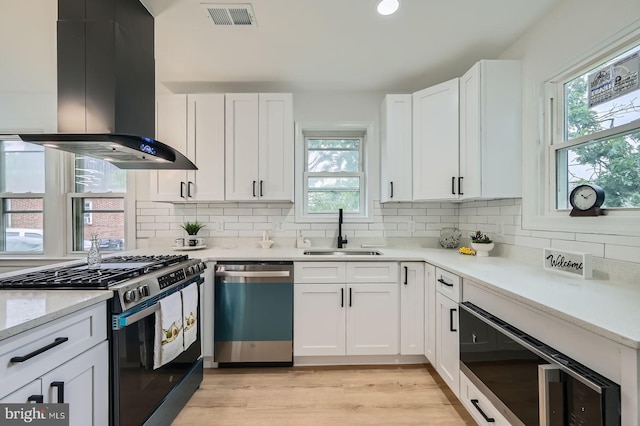 3814 Cedardale Rd, Baltimore, MD 21215 - kitchen featuring dishwashing machine, stainless steel range with gas cooktop, island range hood, white cabinets, and decorative backsplash
