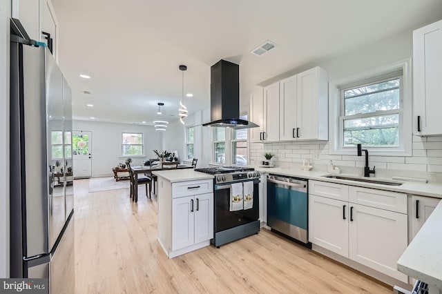 3814 Cedardale Rd, Baltimore, MD 21215 - kitchen featuring appliances with stainless steel finishes, range hood, a peninsula, white cabinetry, and healthy amount of natural light