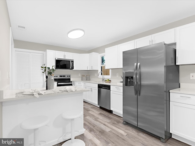 813 Ferguson Rd, Joppa, MD 21085 - kitchen with stainless steel appliances, white cabinets, light wood finished floors, and a breakfast bar area