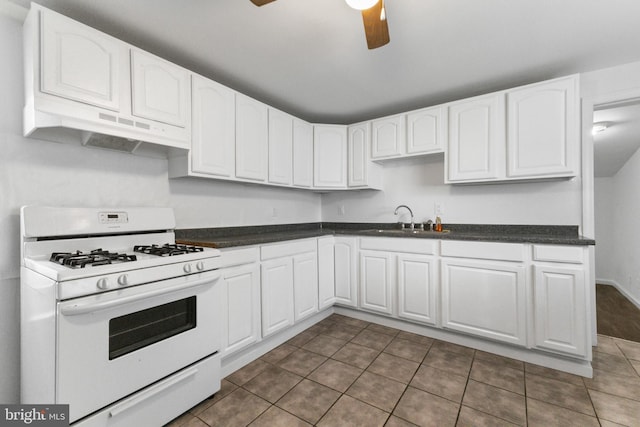 211 Broad St, Beverly, NJ 08010 - kitchen with white range with gas stovetop, under cabinet range hood, ceiling fan, white cabinetry, and dark countertops