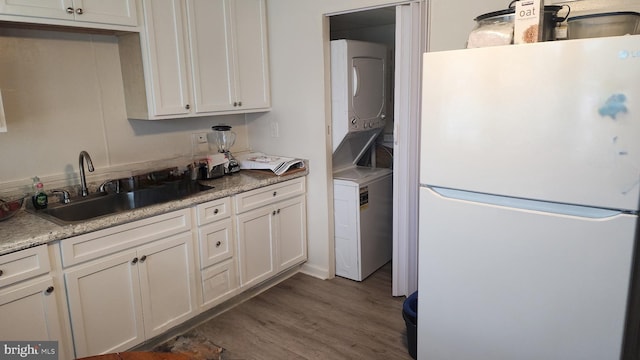 1025 Fredonia Ct, Baltimore, MD 21227 - kitchen with freestanding refrigerator, estacked washer and dryer, dark wood finished floors, white cabinets, and light countertops