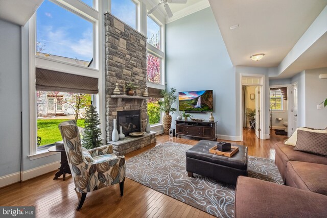 3716 Taft Ave, Alexandria, VA 22304 - living area featuring hardwood / wood-style floors, a towering ceiling, a stone fireplace, crown molding, and a ceiling fan