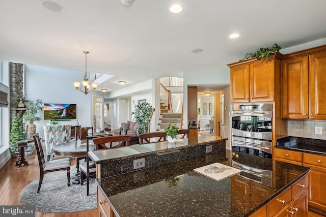 3716 Taft Ave, Alexandria, VA 22304 - kitchen with stainless steel double oven, brown cabinets, wood finished floors, a chandelier, and tasteful backsplash