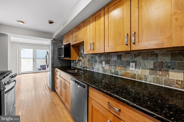 307 S Exeter St, Baltimore, MD 21202 - kitchen with stainless steel appliances, dark stone counters, tasteful backsplash, light wood-style flooring, and brown cabinetry