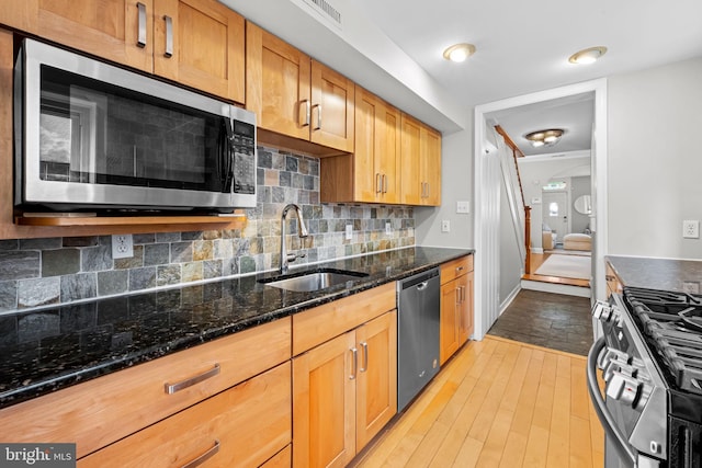 307 S Exeter St, Baltimore, MD 21202 - kitchen featuring appliances with stainless steel finishes, light wood-type flooring, decorative backsplash, and dark stone countertops