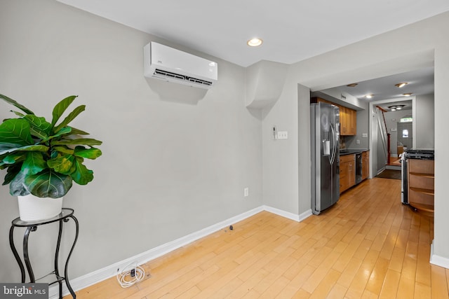 307 S Exeter St, Baltimore, MD 21202 - kitchen with appliances with stainless steel finishes, a wall unit AC, dark countertops, light wood-style flooring, and brown cabinetry