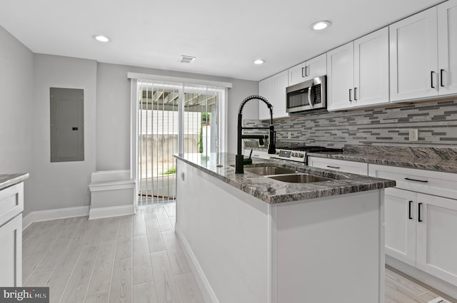 816 Carroll St, Baltimore, MD 21230 - kitchen with stainless steel microwave, electric panel, light wood finished floors, stone countertops, and recessed lighting