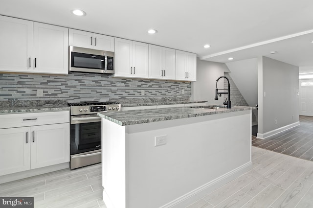 816 Carroll St, Baltimore, MD 21230 - kitchen featuring stainless steel appliances, wood tiled floors, white cabinets, light stone counters, and recessed lighting