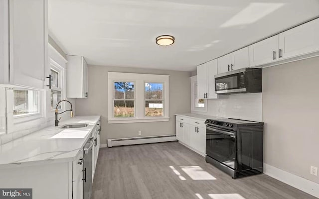 1832 E Buckshutem Rd, Millville, NJ 08332 - kitchen with stainless steel microwave, a baseboard radiator, black range with electric cooktop, light wood-style floors, and decorative backsplash