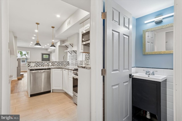 1408 N Redfield St, Philadelphia, PA 19151 - kitchen featuring stainless steel appliances, a peninsula, white cabinets, pendant lighting, and light wood finished floors