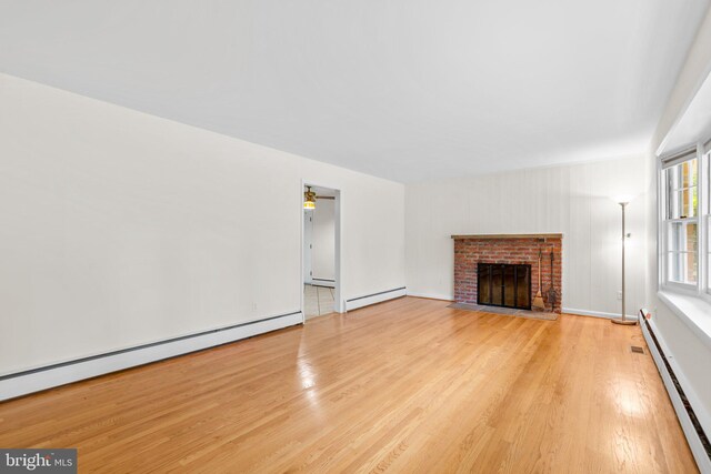 10833 Hunting Ln, Columbia, MD 21044 - unfurnished living room with a baseboard heating unit, light wood-style flooring, baseboard heating, and a brick fireplace