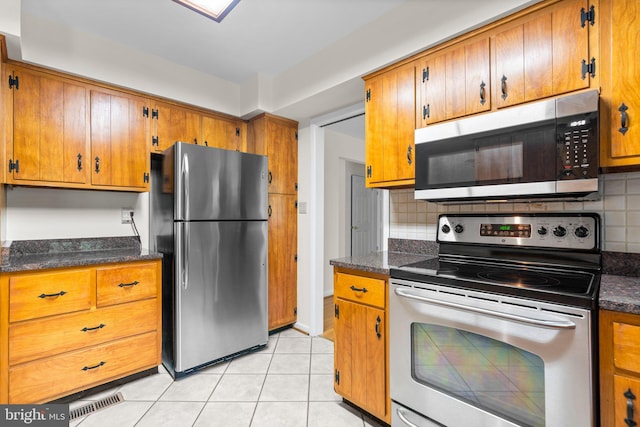10833 Hunting Ln, Columbia, MD 21044 - kitchen featuring appliances with stainless steel finishes, dark countertops, brown cabinetry, and backsplash