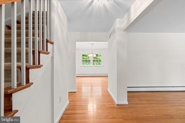 10833 Hunting Ln, Columbia, MD 21044 - hallway featuring a baseboard heating unit, wood finished floors, stairway, and a chandelier