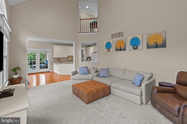 14 Leapson Ln, Doylestown, PA 18901 - living room featuring light colored carpet, french doors, high vaulted ceiling, light wood finished floors, and recessed lighting