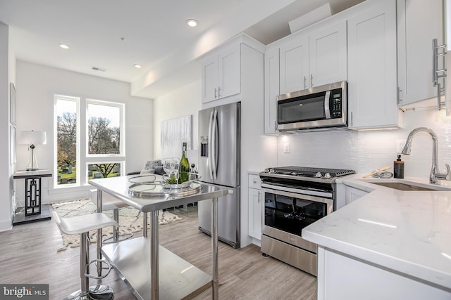 4901 1st St NW Unit 5, Washington, DC 20011 - kitchen with stainless steel appliances, backsplash, light wood-type flooring, light stone countertops, and white cabinets