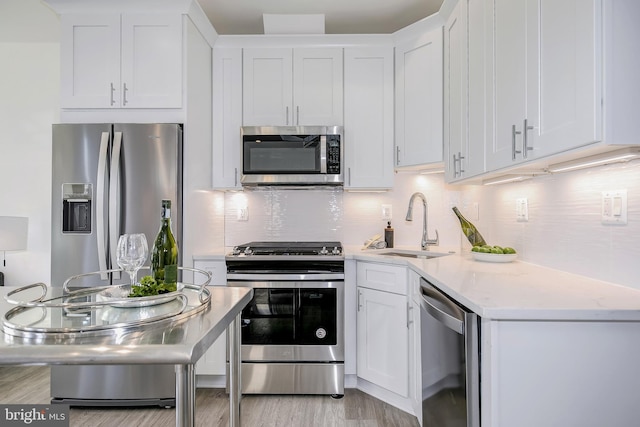 4901 1st St NW Unit 5, Washington, DC 20011 - kitchen with appliances with stainless steel finishes, white cabinets, decorative backsplash, light wood finished floors, and light stone counters