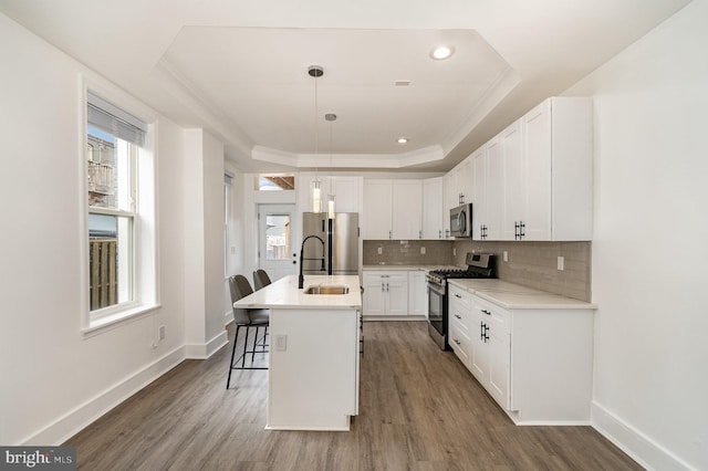 915 N Montford Ave, Baltimore, MD 21205 - kitchen with appliances with stainless steel finishes, wood finished floors, white cabinetry, a kitchen breakfast bar, and tasteful backsplash