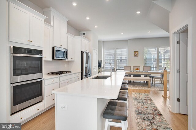 18351 Moss Garden Rd, Dumfries, VA 22026 - kitchen with stainless steel appliances, a kitchen island with sink, a kitchen bar, white cabinets, and recessed lighting