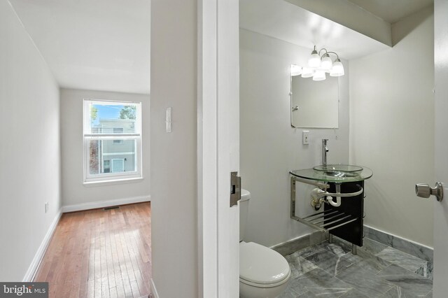 437 Pitman Pl, Baltimore, MD 21202 - half bathroom featuring toilet and wood finished floors