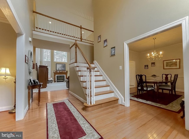 23273 Nicholson St, Hollywood, MD 20636 - foyer featuring light wood-style floors, stairs, a towering ceiling, a chandelier, and a glass covered fireplace