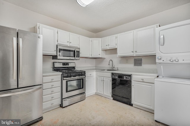 3701 S George Mason Dr Unit 611N, Falls Church, VA 22041 - kitchen with stainless steel appliances, stacked washing machine and dryer, white cabinetry, light countertops, and a textured ceiling