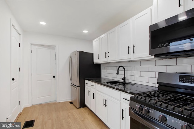 749 Church St, Reading, PA 19601 - kitchen featuring appliances with stainless steel finishes, white cabinetry, backsplash, light wood-type flooring, and recessed lighting
