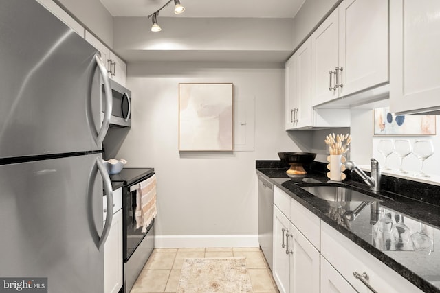 3401 38th St NW Unit 411, Washington, DC 20016 - kitchen with stainless steel appliances, white cabinets, dark stone counters, light tile patterned floors, and track lighting