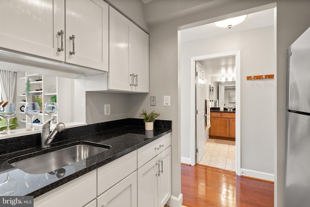 3401 38th St NW Unit 411, Washington, DC 20016 - kitchen with freestanding refrigerator, white cabinets, dark stone counters, and light wood finished floors
