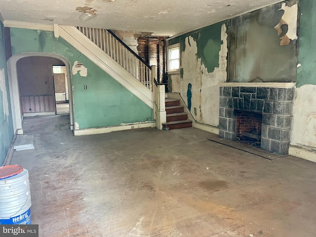 1510 Baird Blvd, Camden, NJ 08103 - unfurnished living room featuring stairs, concrete floors, a stone fireplace, arched walkways, and a textured ceiling