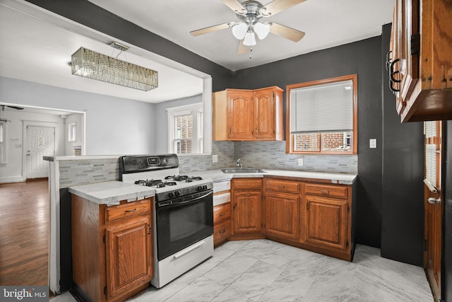 7019 Algard St, Philadelphia, PA 19135 - kitchen featuring gas range, a ceiling fan, light countertops, decorative backsplash, and a peninsula