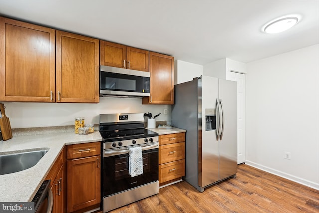 24 Whitechurch Ct, Germantown, MD 20874 - kitchen with stainless steel appliances, light wood-style flooring, and brown cabinetry