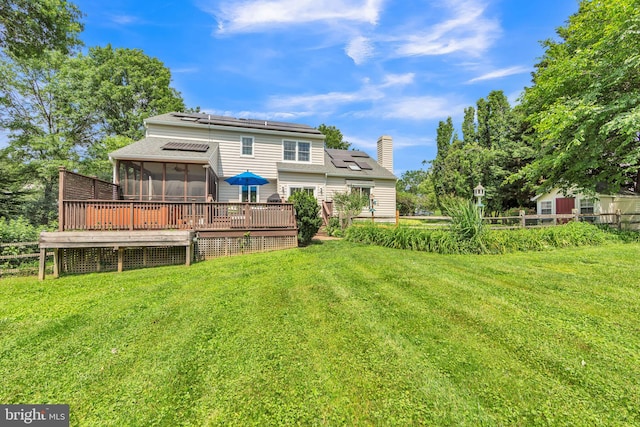 5 Yarmouth Ln, Downingtown, PA 19335 - rear view of house featuring a sunroom, roof mounted solar panels, a wooden deck, a chimney, and roof with shingles