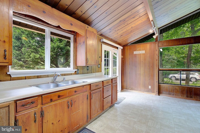 638 Los Alamos Ln, Lusby, MD 20657 - kitchen featuring lofted ceiling, wood walls, light countertops, healthy amount of natural light, and light floors