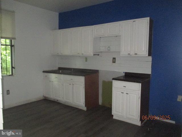 1142 W Nevada St, Philadelphia, PA 19133 - kitchen with dark wood finished floors, white cabinets, and dark countertops