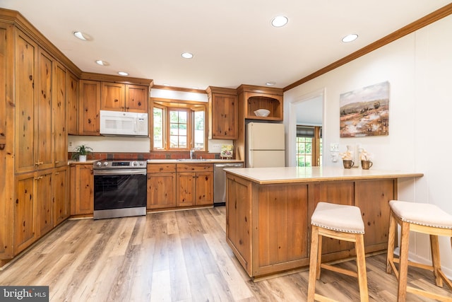 559 Maple Ave, Doylestown, PA 18901 - kitchen with appliances with stainless steel finishes, ornamental molding, brown cabinetry, a peninsula, and recessed lighting