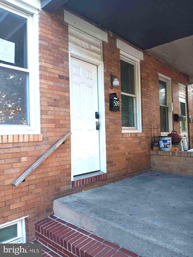 509 N Highland Ave, Baltimore, MD 21205 - doorway to property featuring brick siding and covered porch