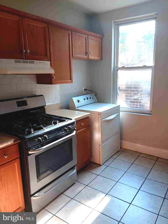 509 N Highland Ave, Baltimore, MD 21205 - kitchen with stainless steel range with gas stovetop, under cabinet range hood, washer / clothes dryer, light tile patterned floors, and backsplash